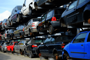 An image of a car scrap yard, with vehicles stacked on top of one another.